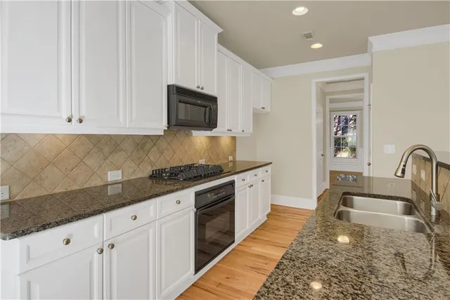 a kitchen with granite countertop a sink stainless steel appliances and white cabinets