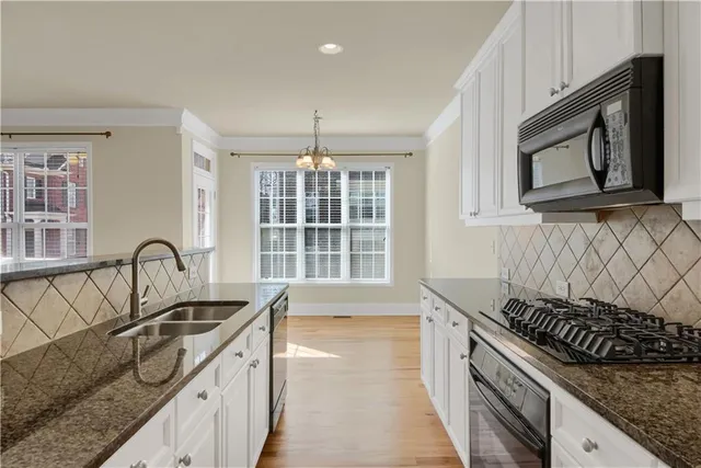 a kitchen with granite countertop a sink stove and cabinets