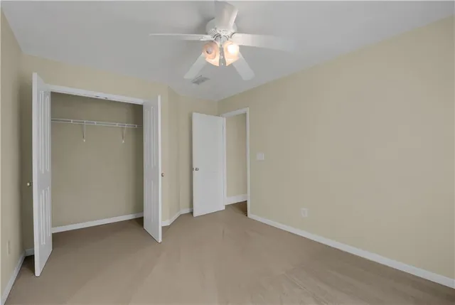 an empty room with a chandelier fan and closet area