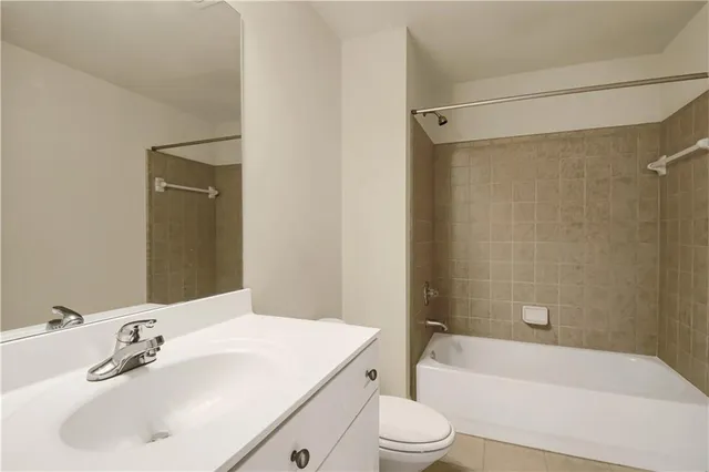 a bathroom with a bathtub shower sink vanity mirror and toilet