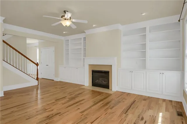 a view of an empty room with wooden floor and a fireplace