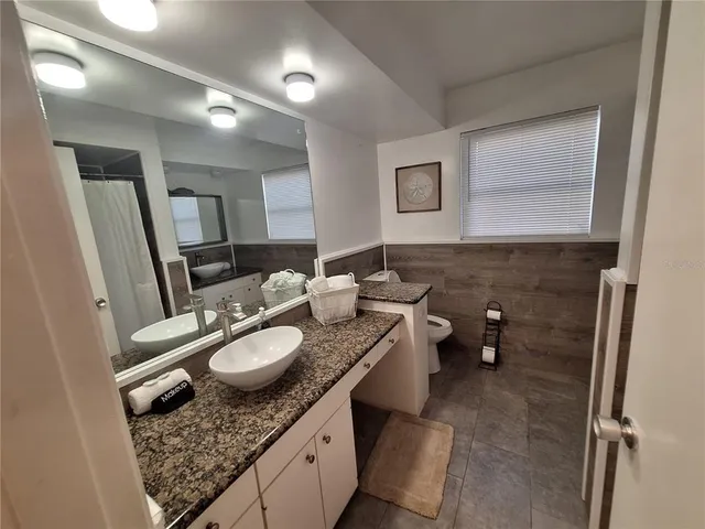 a bathroom with a granite countertop sink mirror vanity and toilet