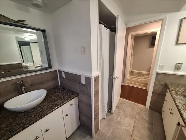 a bathroom with a granite countertop sink a mirror and a shower