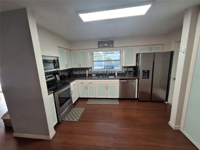 a kitchen with a sink a refrigerator a window and a counter top space