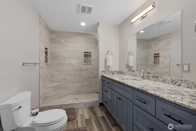 a bathroom with a granite countertop bathtub shower sink mirror vanity toilet and a shower