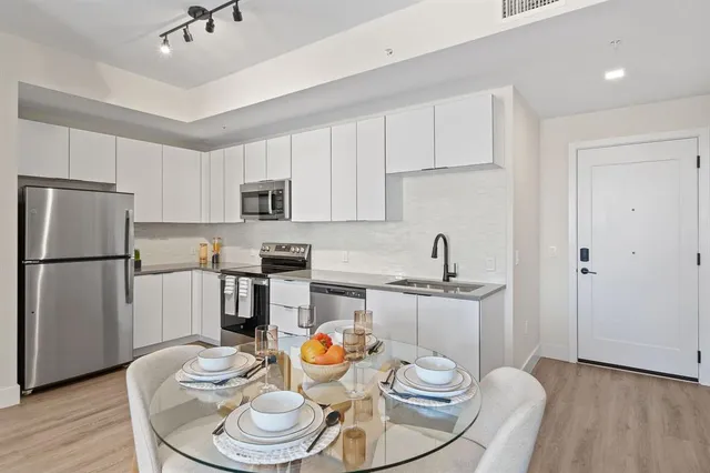 a kitchen with stainless steel appliances kitchen island granite countertop a dining table and chairs