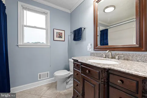 a bathroom with a granite countertop toilet sink and mirror
