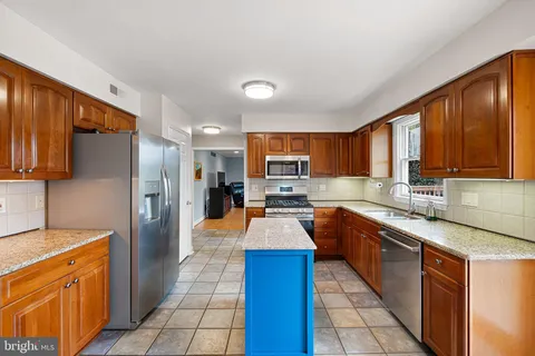 a large kitchen with stainless steel appliances granite countertop a sink counter space cabinets and a large window