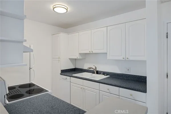 a kitchen with granite countertop white cabinets and a sink