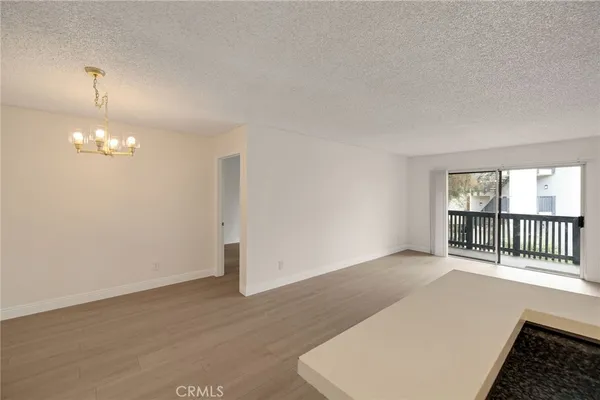 an empty room with wooden floor chandelier and windows