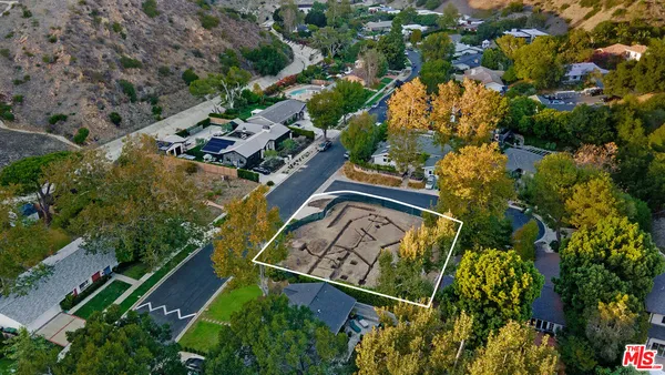 an aerial view of a house swimming pool and large trees