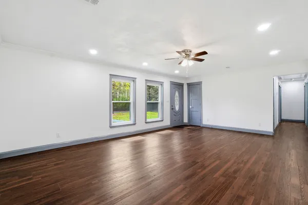 a view of an empty room with a window and wooden floor