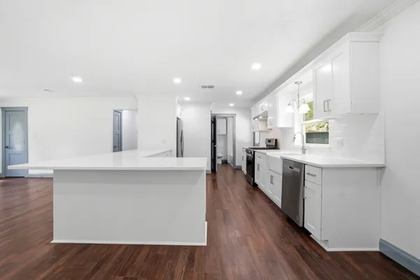 a large kitchen with stainless steel appliances kitchen island a large counter top and a wooden floors