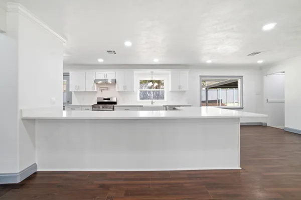 a large white kitchen with lots of counter space and wooden floor
