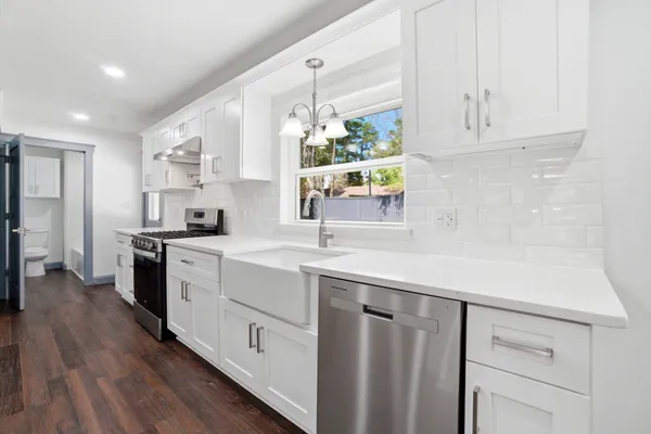 a kitchen with white cabinets and sink