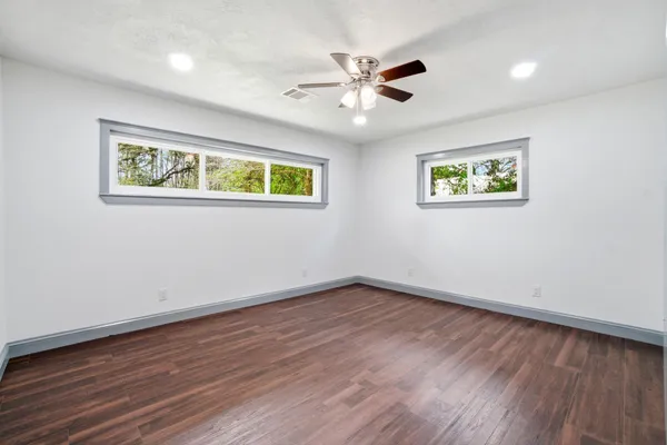 a view of an empty room with wooden floor and a window