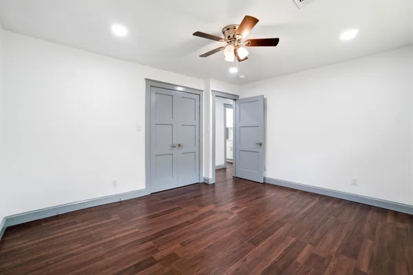 an empty room with wooden floor and a ceiling fan