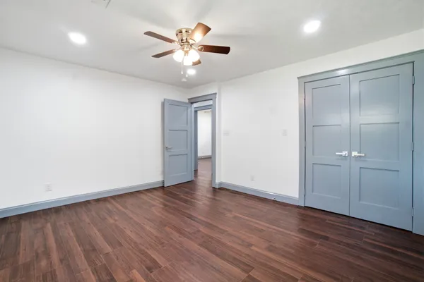 an empty room with wooden floor and chandelier fan
