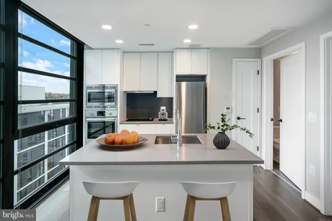 a kitchen with stainless steel appliances a dining table chairs and refrigerator