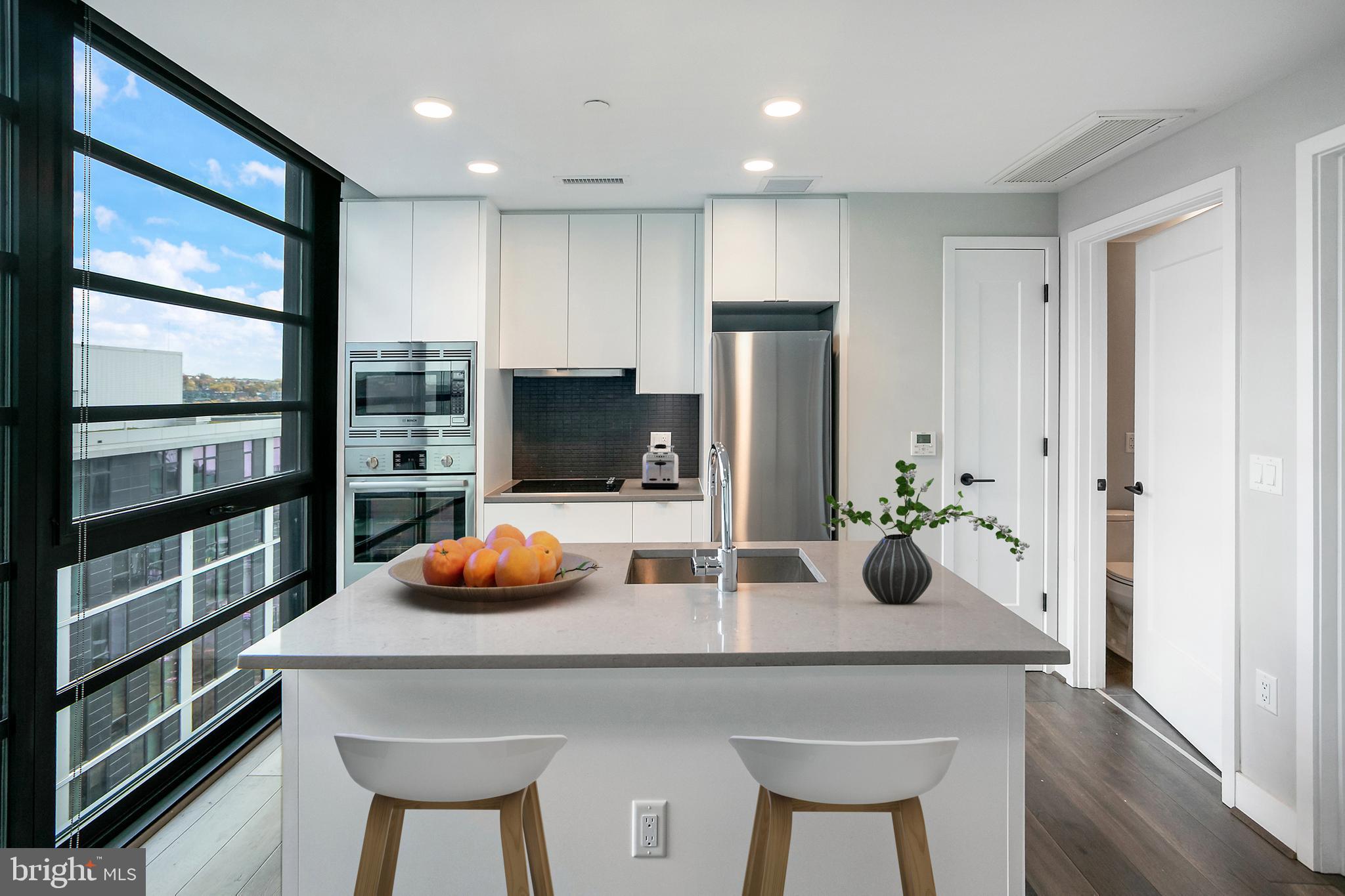 1300 4th Street Southeast, Unit 901 Washington, DC 20003 - Photo 7 of 27 a kitchen with stainless steel appliances a dining table chairs and refrigerator