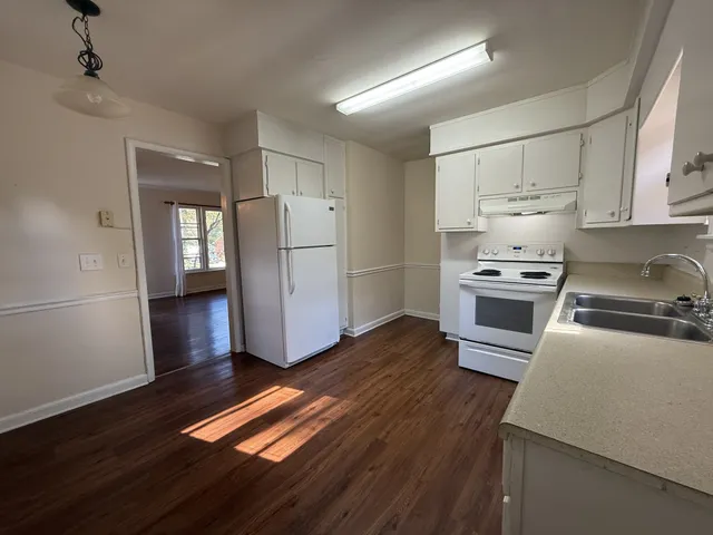 a kitchen with granite countertop wooden floors a stove and a refrigerator