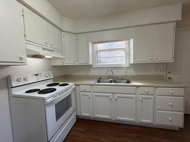 a kitchen with cabinets appliances a sink and a window
