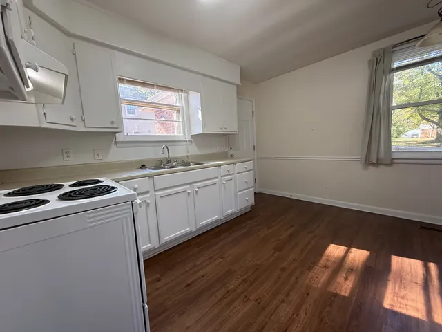 a kitchen with a sink a stove cabinets and wooden floor