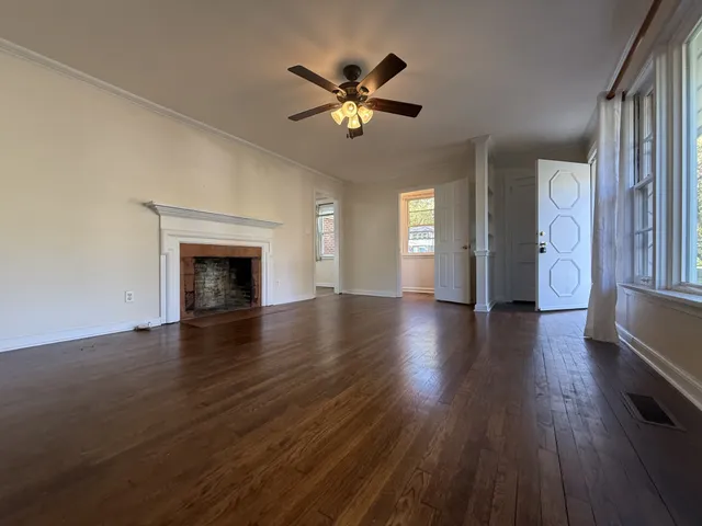 a view of an empty room with a fireplace and wooden floor