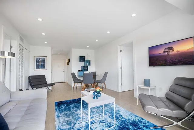 a living room with furniture a flat screen tv and kitchen view
