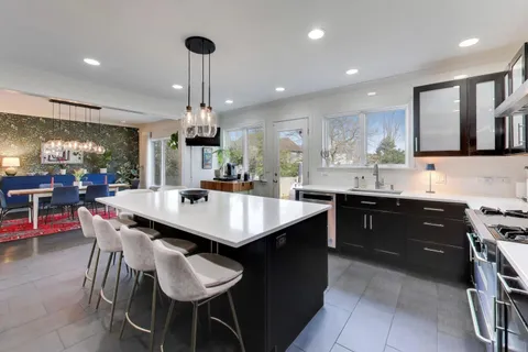 a kitchen with a dining table chairs sink and cabinets