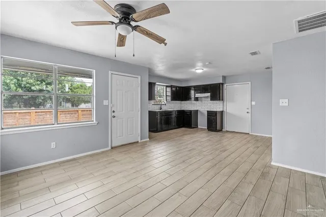 a view of kitchen and empty room with wooden floor and windows