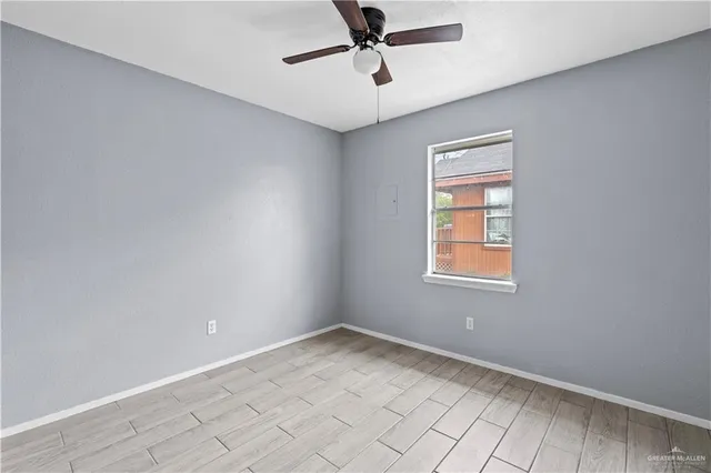 an empty room with windows and fan