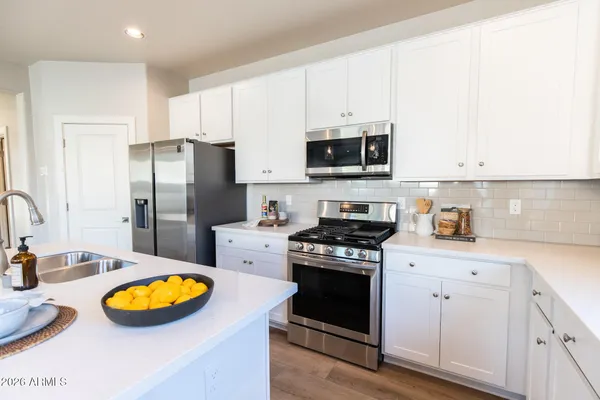 a kitchen with stainless steel appliances a refrigerator a stove a sink a dining table and chairs