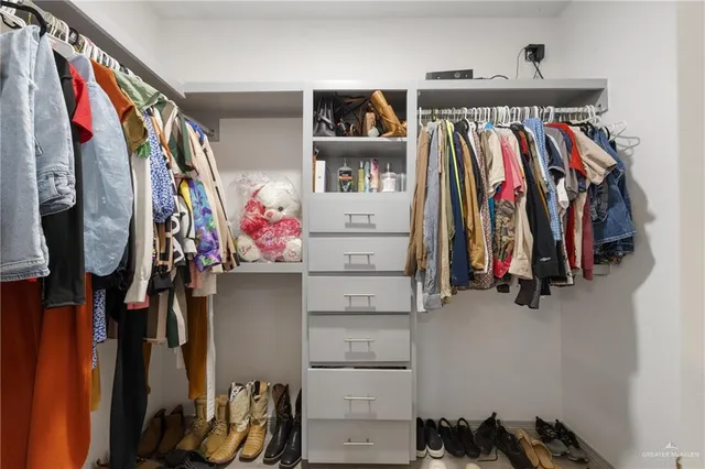 a view of walk in closet with clothes and shoes