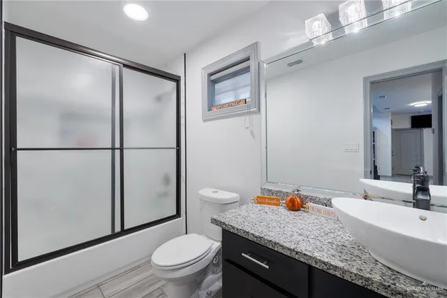 a bathroom with a granite countertop sink toilet and shower