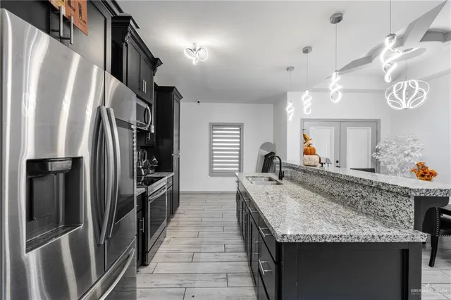 a kitchen with stainless steel appliances granite countertop a sink and a refrigerator