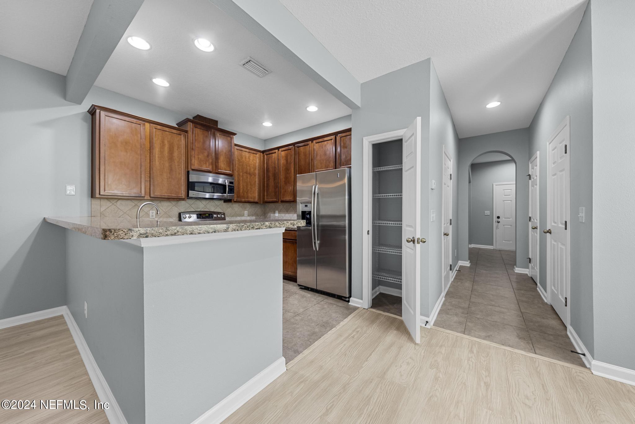 12939 Spring Rain Road Jacksonville, FL 32258 - Photo 7 of 30 a kitchen with refrigerator a microwave and cabinets