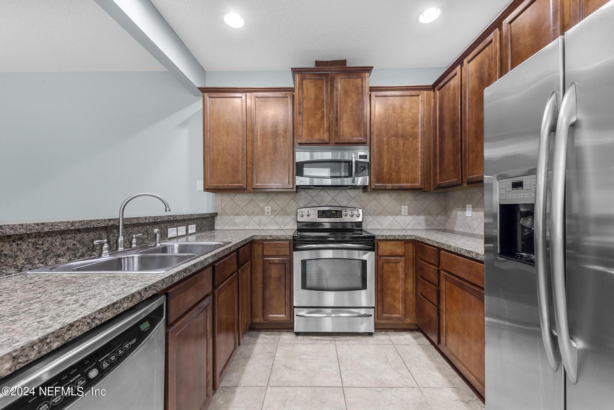 12939 Spring Rain Road Jacksonville, FL 32258 - Photo 9 of 30 a kitchen with stainless steel appliances granite countertop a sink stove and refrigerator