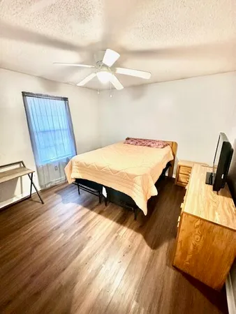 a bedroom with wooden floor and ceiling fan
