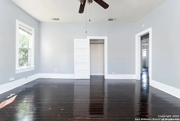 a view of an empty room with window and wooden floor