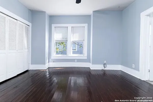 a view of empty room with wooden floor and fan