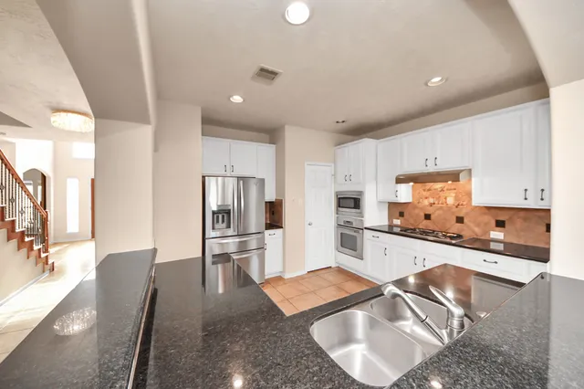 a kitchen with stainless steel appliances granite countertop a sink refrigerator and cabinets