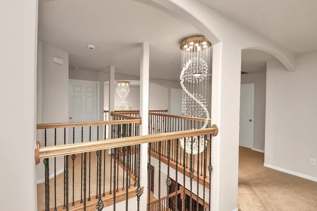 a view of staircase with railing and a chandelier
