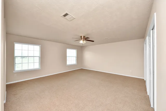 an empty room with windows and ceiling fan