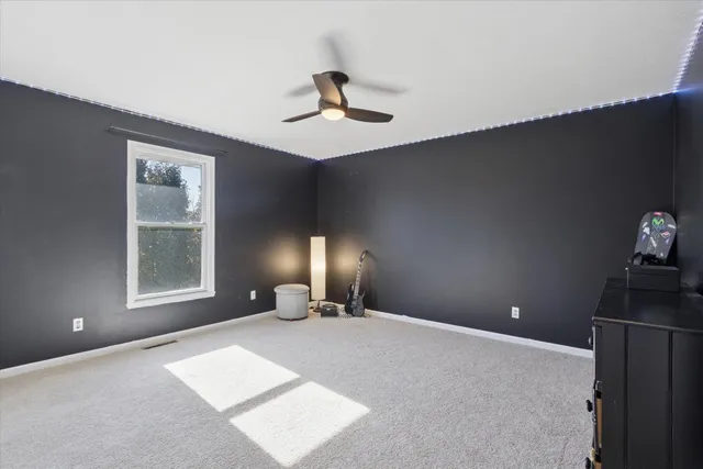 a view of an empty room with chandelier fan and a window