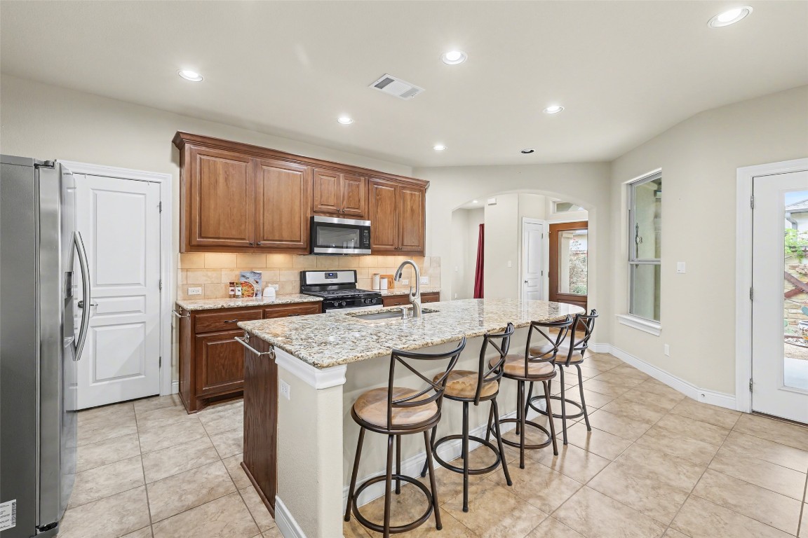 116 Trailing Lantana Drive, Unit G Georgetown, TX 78628 - Photo 12 of 38 a kitchen with stainless steel appliances granite countertop a stove a sink a refrigerator and a dining table with wooden cabinet