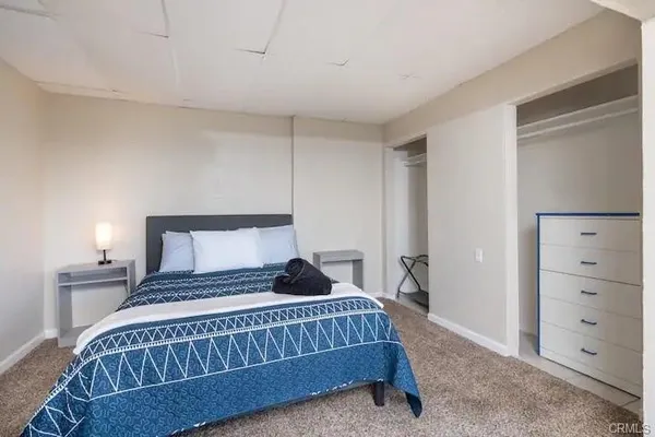 a bedroom with a large bed and a lamp on dresser