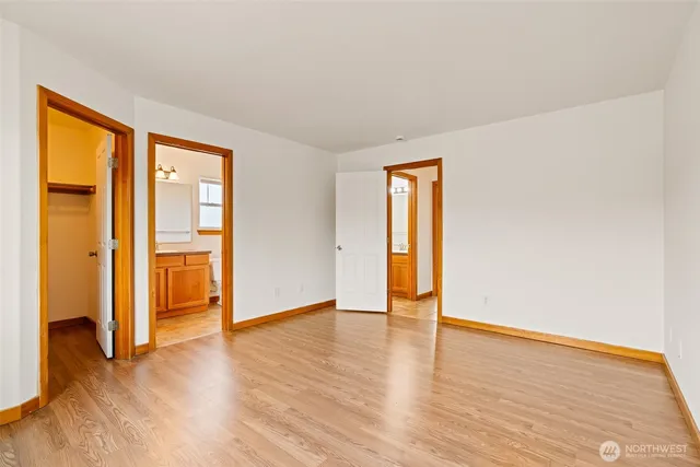 a spacious bedroom with a bed and a lamp on dresser