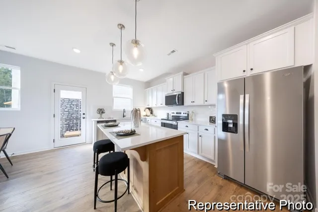 a kitchen with stainless steel appliances kitchen island a refrigerator a stove a sink a dining table and chairs