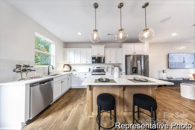 a kitchen with stainless steel appliances granite countertop a sink a stove a refrigerator and island with wooden floor
